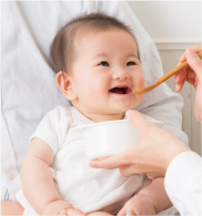 赤ちゃんが笑いながら離乳食を食べている写真